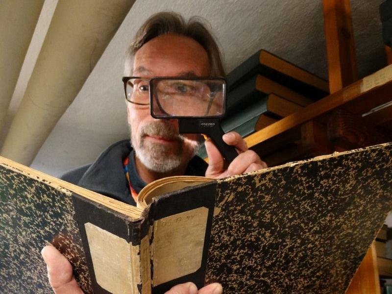 Henrik i kælderen, med en lup og en gammel bog